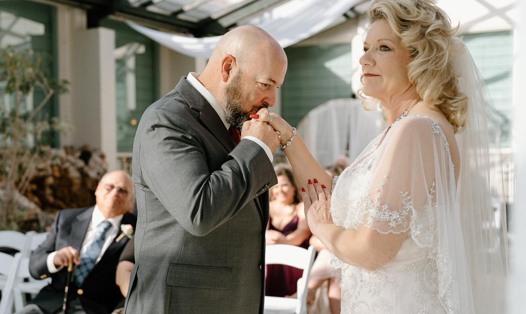 Emotional wedding ceremony at The Brown Estate in Orange, Texas as the groom wipes away tears beside his bride.
